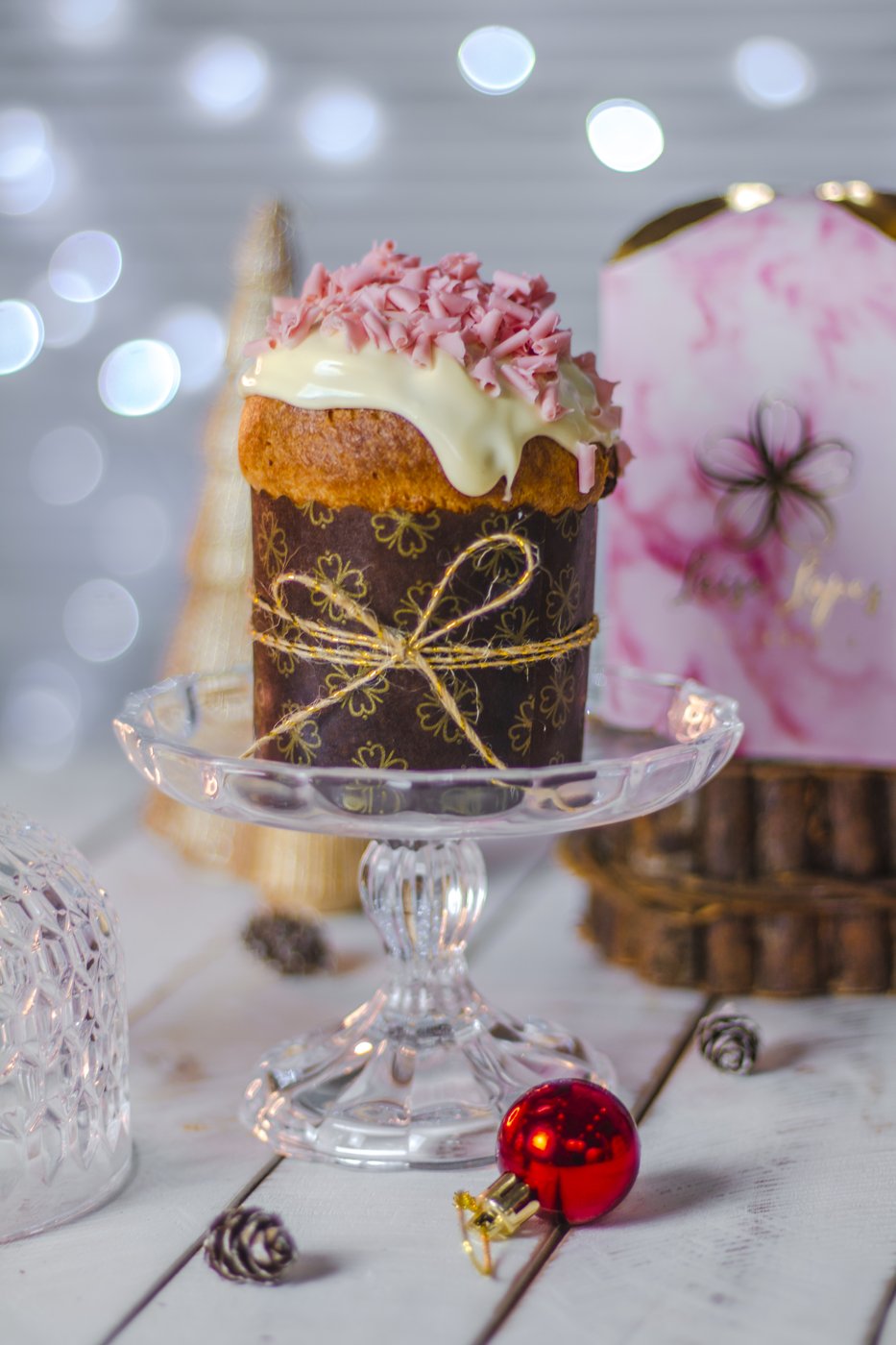 Panetone de Natal com cobertura e laço dourado em suporte de vidro